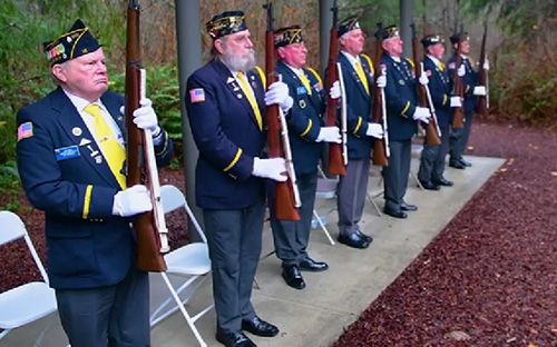 Seven members of a Veterans Service Organization (VSO) present arms while performing military funeral honors at a national cemetery.