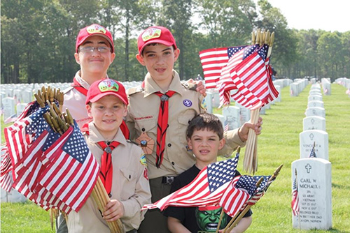 Boy Scouts holding American flags to place at headstones at a national cemetery.