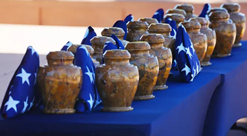 Urns and American flags atop a table during a burial service for 18 unclaimed Veterans at the National Memorial Cemetery of Arizona, August 31, 2022.