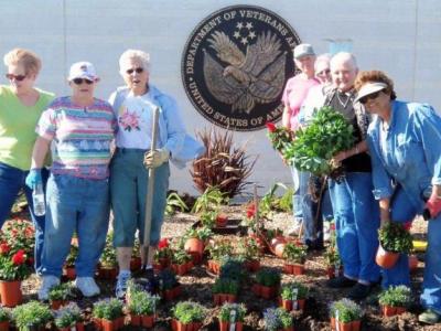 volunteers plant flowers at cemetery entrance